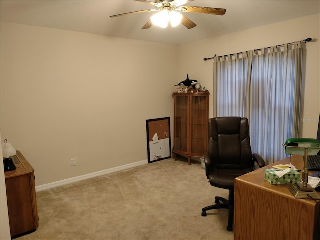 office space featuring light carpet, a ceiling fan, and baseboards