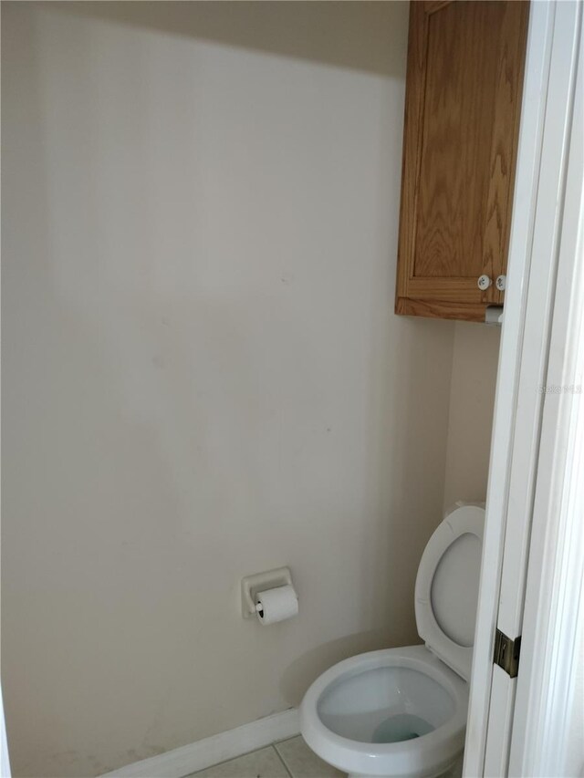 bathroom with tile patterned flooring, toilet, and baseboards