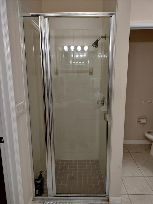 full bathroom with baseboards, a stall shower, toilet, and tile patterned floors