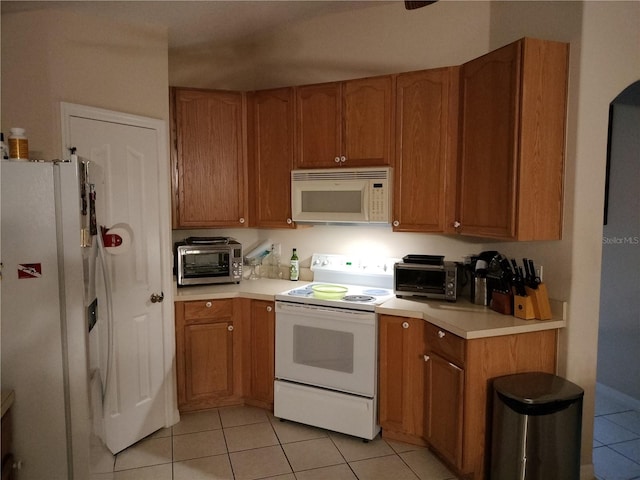 kitchen with a toaster, white appliances, light countertops, and light tile patterned flooring