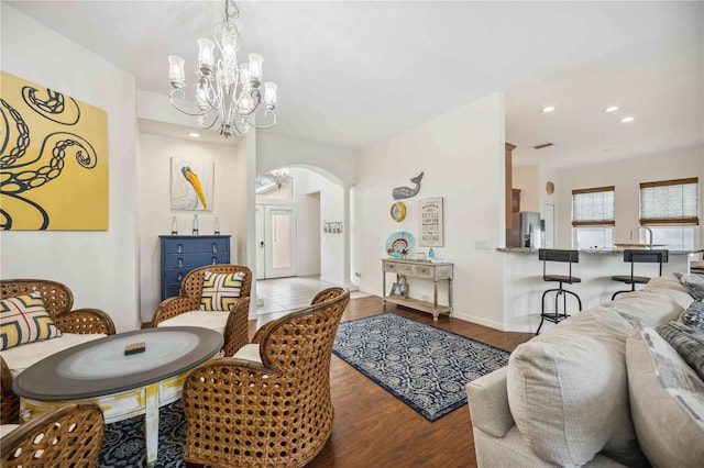 living room featuring baseboards, arched walkways, wood finished floors, an inviting chandelier, and recessed lighting