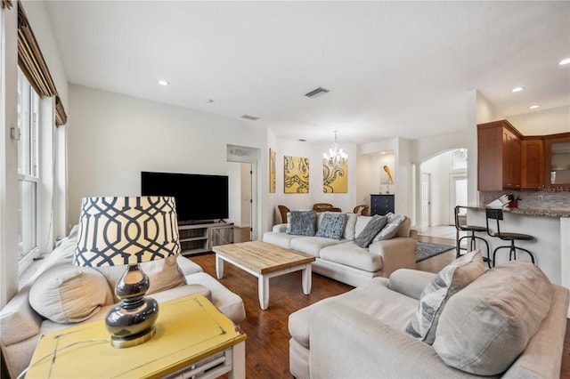 living area featuring visible vents, arched walkways, dark wood-style floors, a chandelier, and recessed lighting