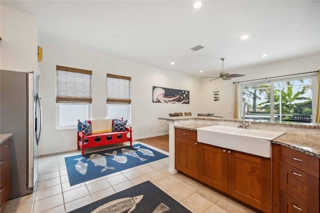 kitchen featuring plenty of natural light, freestanding refrigerator, visible vents, and a sink