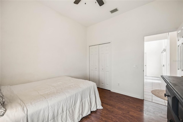 bedroom featuring ceiling fan, dark wood-type flooring, visible vents, baseboards, and a closet