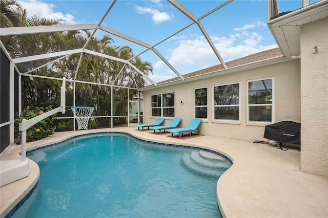 outdoor pool featuring a patio area, glass enclosure, and area for grilling