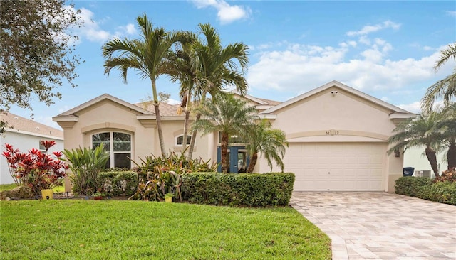 mediterranean / spanish home with a garage, a front yard, decorative driveway, and stucco siding