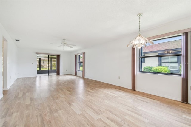 unfurnished room featuring light wood-style flooring, visible vents, and ceiling fan with notable chandelier