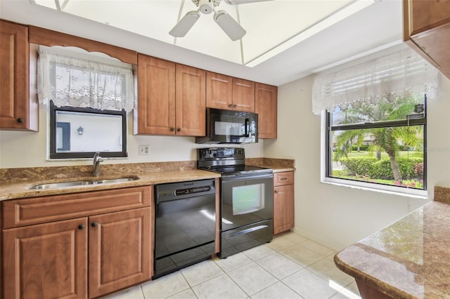 kitchen with light tile patterned floors, ceiling fan, a sink, brown cabinets, and black appliances