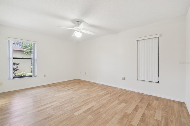 empty room with baseboards, a textured ceiling, and light wood finished floors