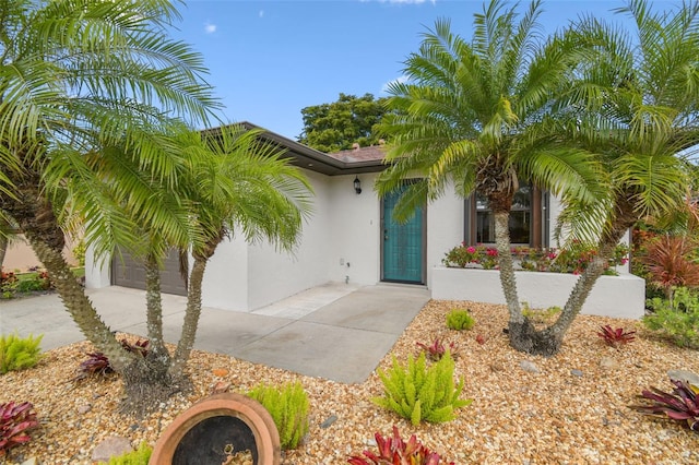 entrance to property with a garage and stucco siding