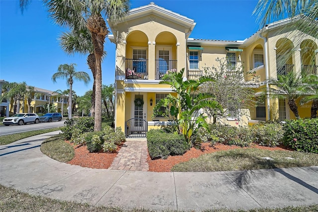 view of front of house featuring a balcony, a gate, and stucco siding