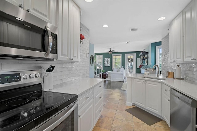 kitchen with appliances with stainless steel finishes, a sink, and white cabinetry