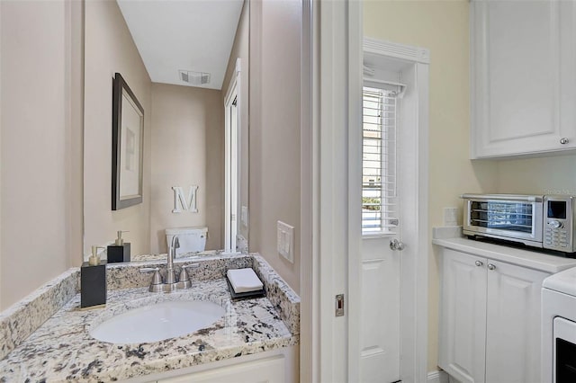 bathroom with toilet, visible vents, washer / clothes dryer, and vanity