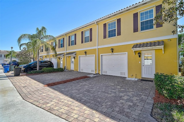 view of property featuring driveway, an attached garage, and stucco siding