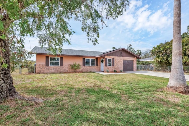 single story home featuring concrete driveway, a front yard, fence, a garage, and stone siding