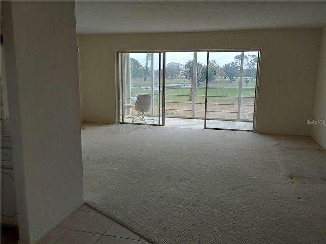 unfurnished room featuring light tile patterned flooring and light colored carpet