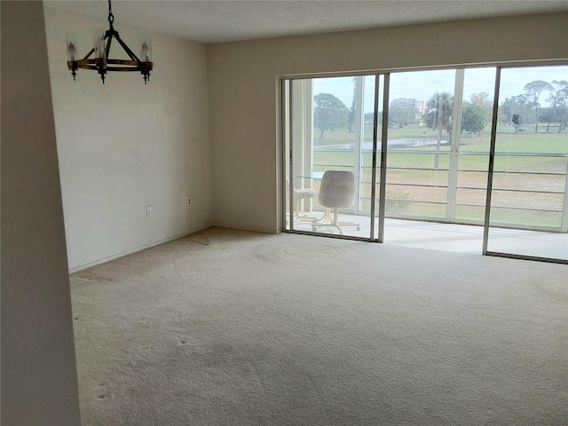 carpeted empty room with a textured ceiling and an inviting chandelier