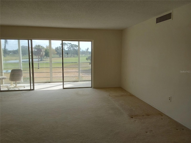 carpeted spare room featuring visible vents and a textured ceiling