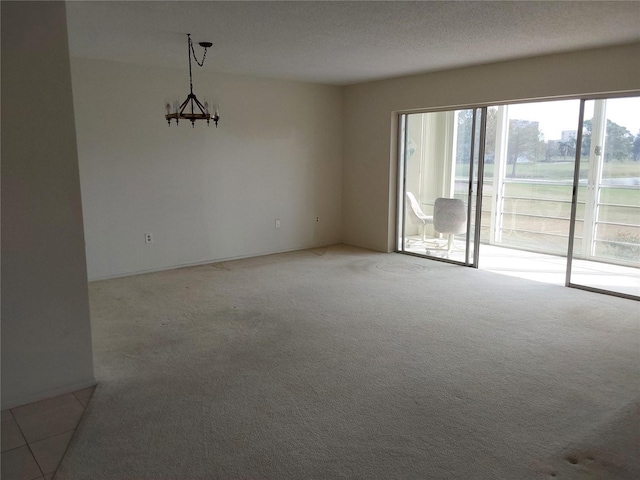 unfurnished room featuring a textured ceiling, carpet floors, and an inviting chandelier