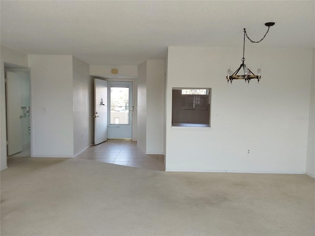 unfurnished room featuring light tile patterned floors, a chandelier, and light colored carpet