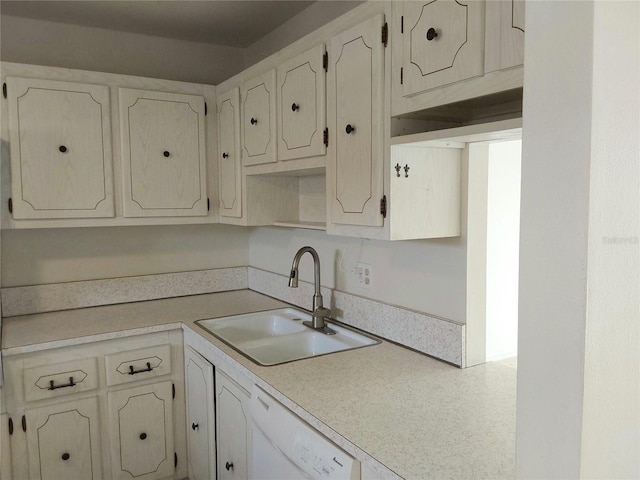 kitchen with white dishwasher, white cabinetry, light countertops, and a sink