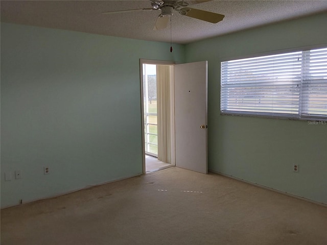 unfurnished room featuring a textured ceiling, ceiling fan, and light colored carpet