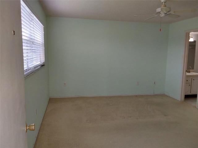 spare room featuring a ceiling fan, light colored carpet, and a sink