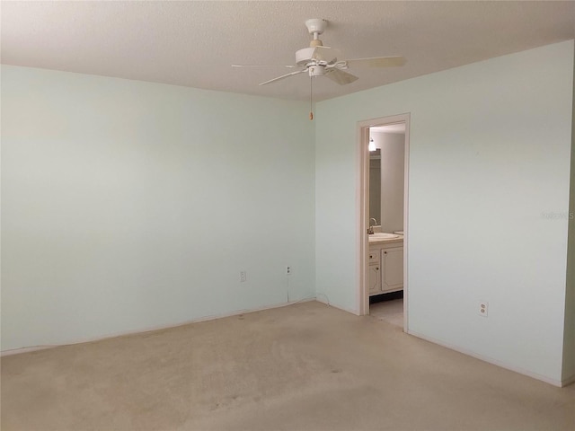 unfurnished bedroom featuring ensuite bath, a ceiling fan, a sink, and light colored carpet