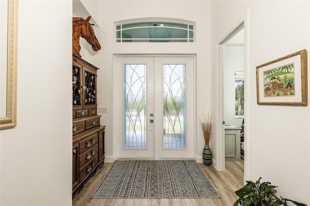 doorway with french doors, light wood-style flooring, and baseboards