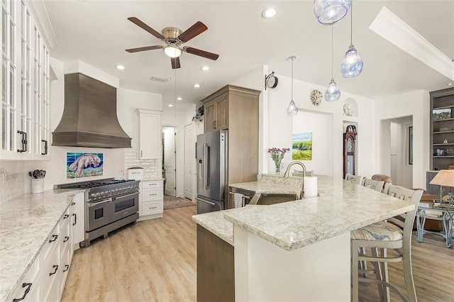 kitchen featuring high quality appliances, a sink, white cabinetry, and custom range hood