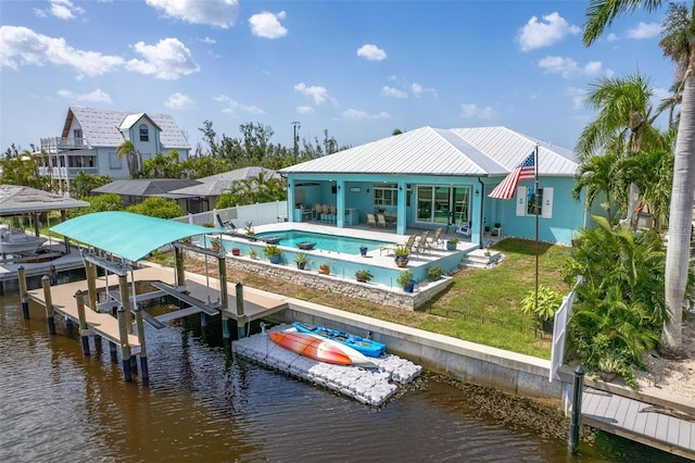 back of property featuring a patio, a water view, boat lift, and a fenced in pool