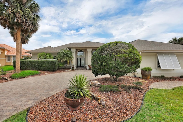 view of front of home featuring driveway, stucco siding, a shingled roof, and french doors