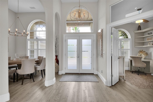 entryway with french doors, a notable chandelier, a high ceiling, and wood finished floors