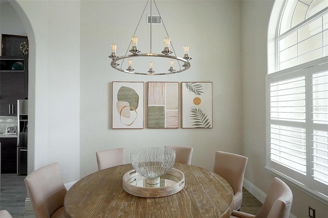 dining room with arched walkways, plenty of natural light, baseboards, and a notable chandelier