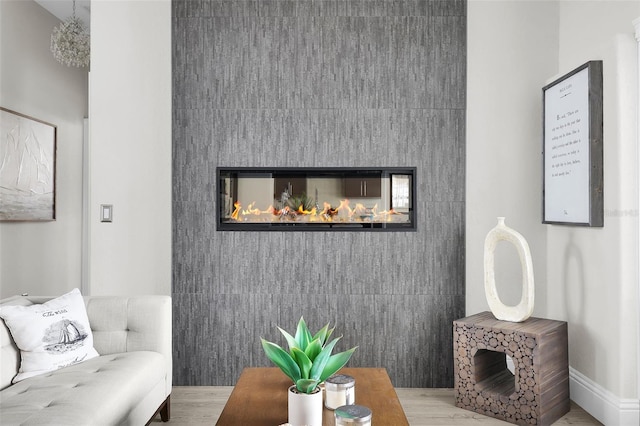 living room with an accent wall, wood finished floors, and a glass covered fireplace