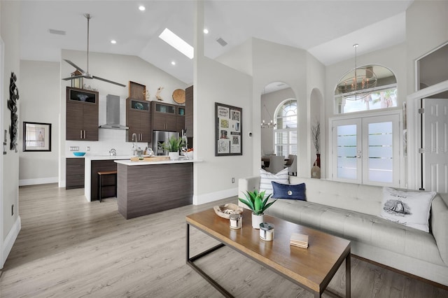 living area featuring high vaulted ceiling, visible vents, baseboards, light wood-style floors, and french doors