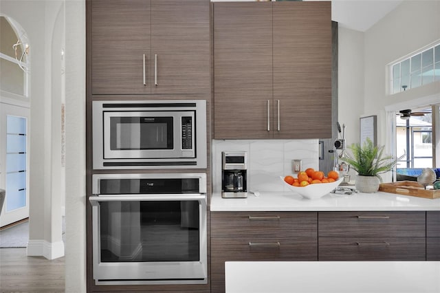 kitchen featuring modern cabinets, stainless steel appliances, decorative backsplash, and wood finished floors