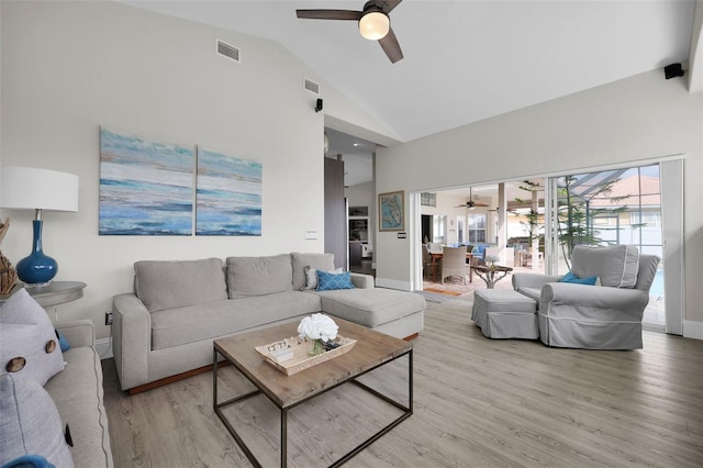 living area featuring light wood finished floors, visible vents, a ceiling fan, high vaulted ceiling, and baseboards