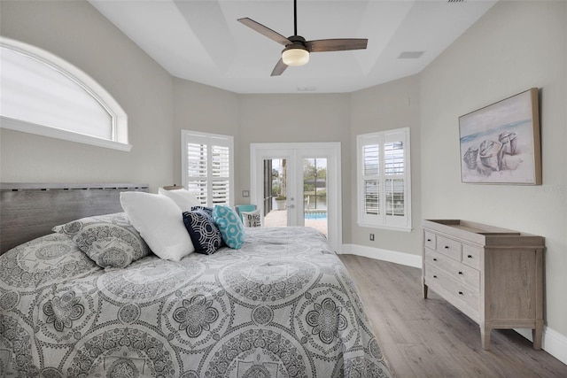 bedroom featuring access to outside, french doors, a tray ceiling, and baseboards