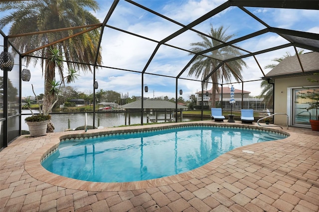 outdoor pool featuring glass enclosure, a patio area, and a water view