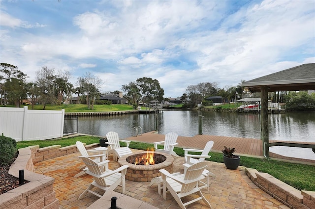 view of patio with a water view, an outdoor fire pit, fence, and a boat dock