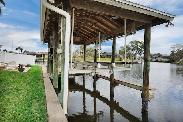 view of dock with a yard, a water view, boat lift, and fence