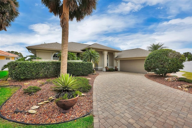 view of front facade with decorative driveway, an attached garage, and stucco siding