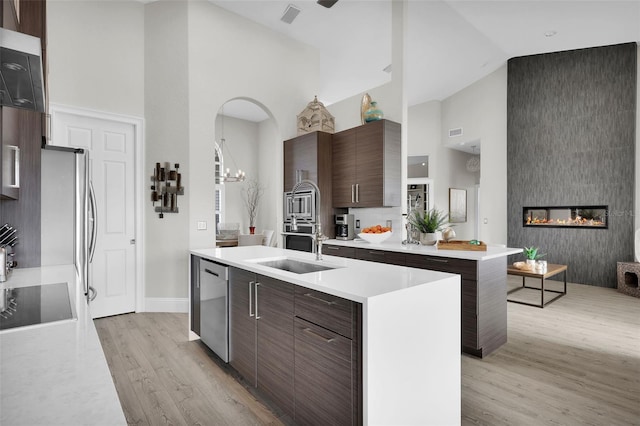 kitchen featuring dishwasher, high vaulted ceiling, modern cabinets, and a center island with sink