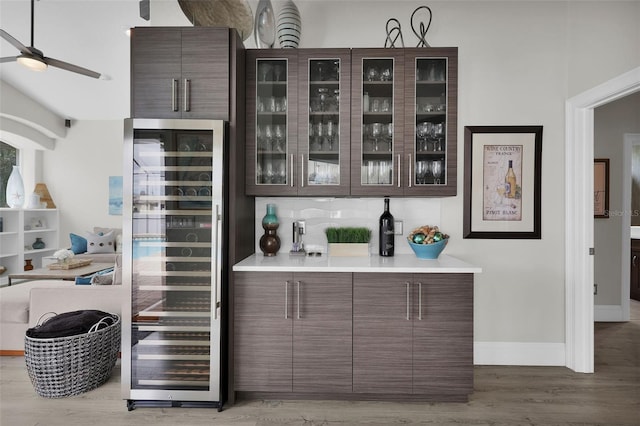 bar with a dry bar, light wood finished floors, tasteful backsplash, baseboards, and wine cooler