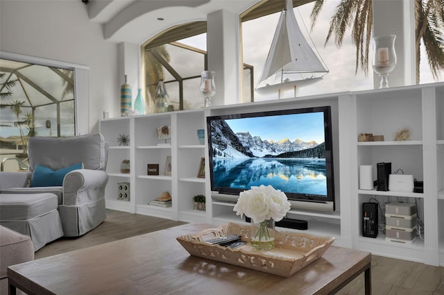 living area with built in shelves, plenty of natural light, and wood finished floors