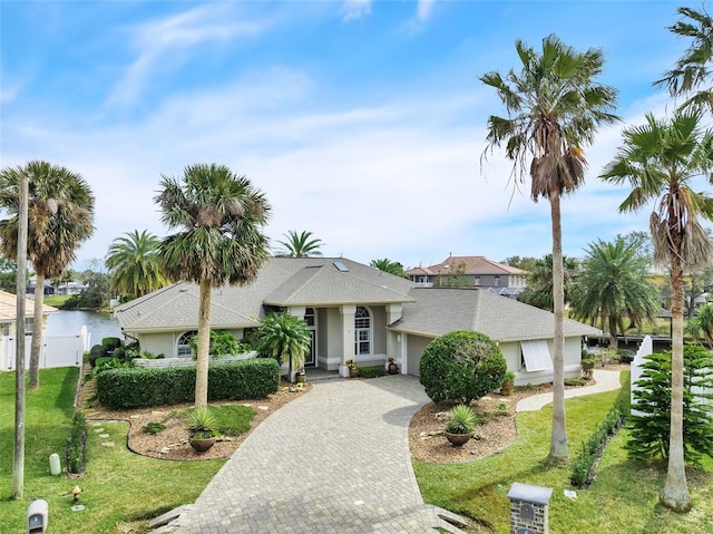 view of front of property featuring a garage, fence, decorative driveway, stucco siding, and a front yard