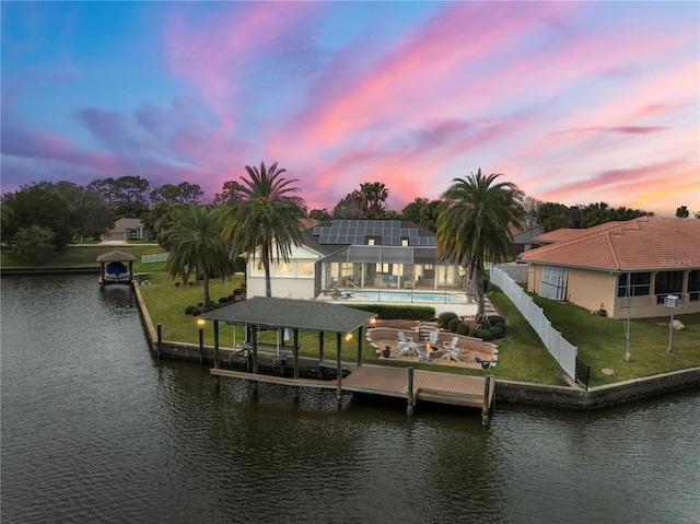 view of dock featuring a water view, a lawn, a fenced backyard, boat lift, and an outdoor pool