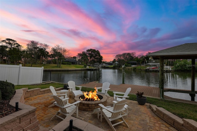 view of patio / terrace with a fire pit, a water view, and fence