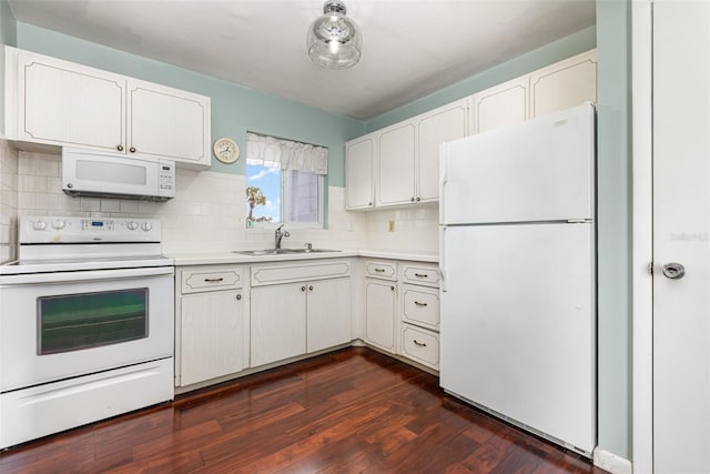 kitchen with dark wood finished floors, light countertops, decorative backsplash, a sink, and white appliances